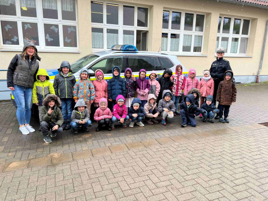 Das Bild ist ein Gruppenbild der Vorschulkinder der Kita Niedershausen vor einem Polizeiauto